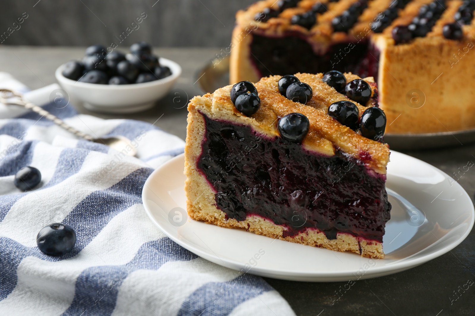 Photo of Slice of delicious homemade blueberry pie served on grey table, closeup