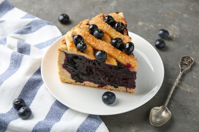 Photo of Slice of delicious homemade blueberry pie served on grey table, closeup