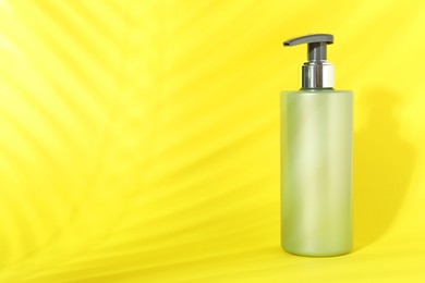 Photo of Shampoo in bottle on yellow background, space for text