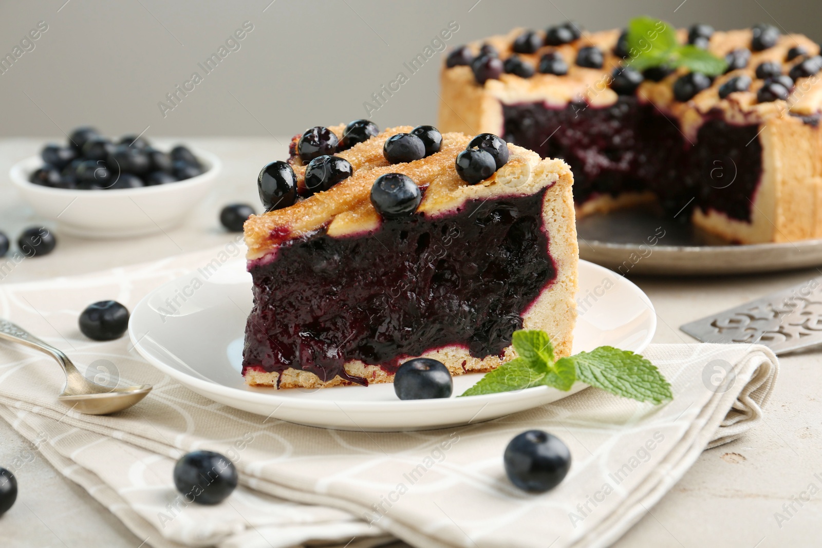 Photo of Slice of delicious homemade blueberry pie served on light table, closeup