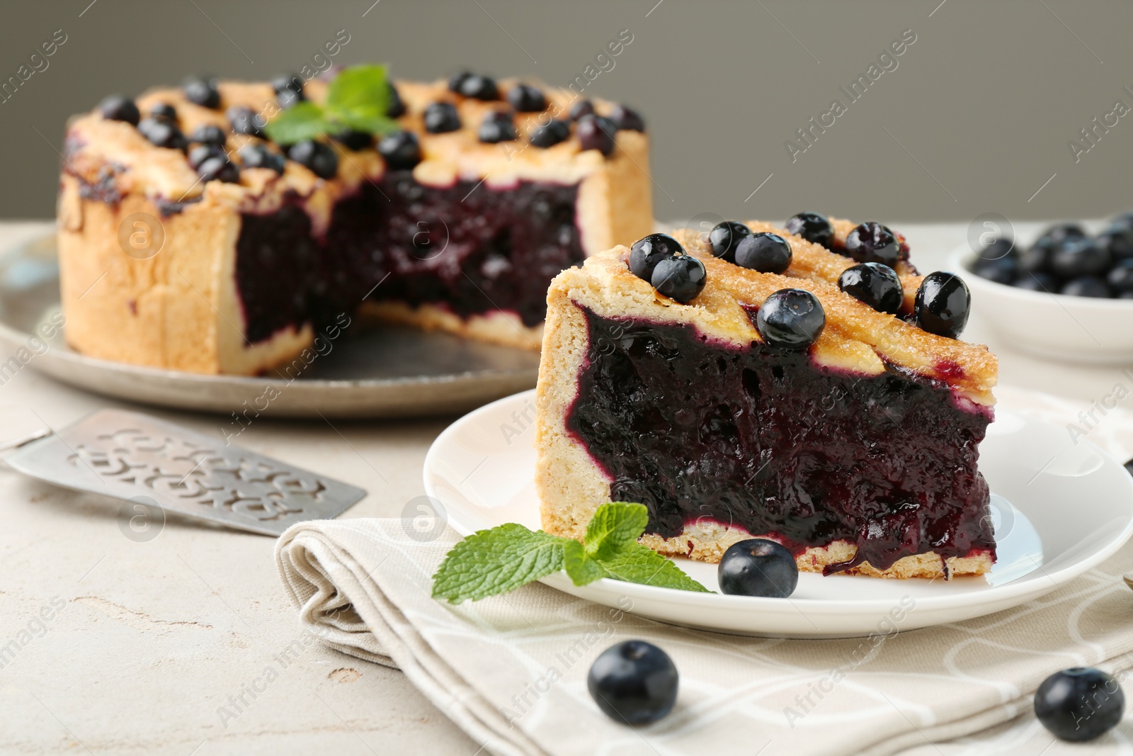 Photo of Slice of delicious homemade blueberry pie served on light table, closeup