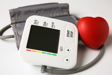 Photo of Blood pressure measuring device and squeeze heart on white background, closeup