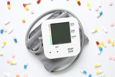 Blood pressure measuring device and pills on white background, top view