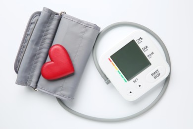 Photo of Blood pressure measuring device and heart figure on white background, top view