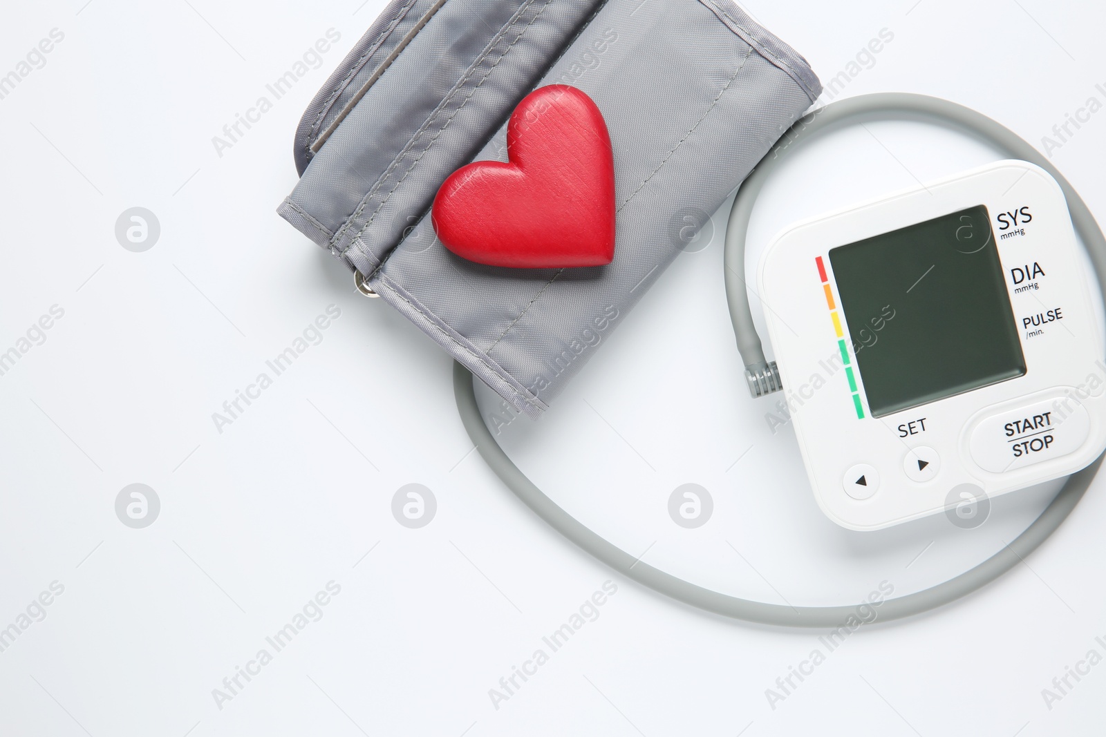 Photo of Blood pressure measuring device and heart figure on white background, top view. Space for text