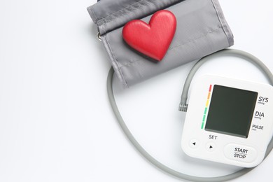 Photo of Blood pressure measuring device and heart figure on white background, top view. Space for text