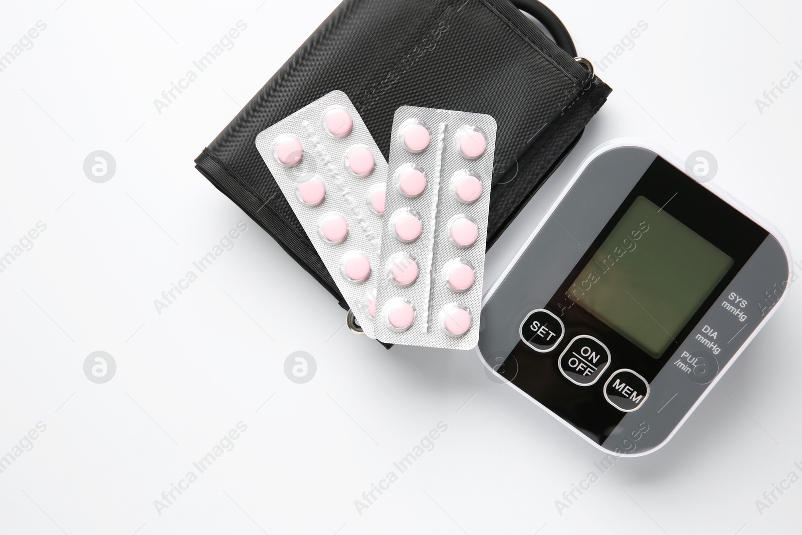 Photo of Blood pressure measuring device and pills on white background, top view