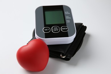 Blood pressure measuring device and squeeze heart on white background, closeup