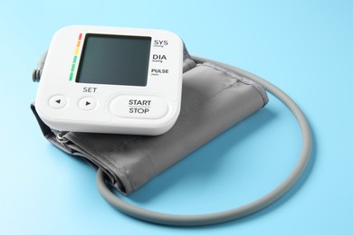 Photo of Blood pressure measuring device on light blue background, closeup