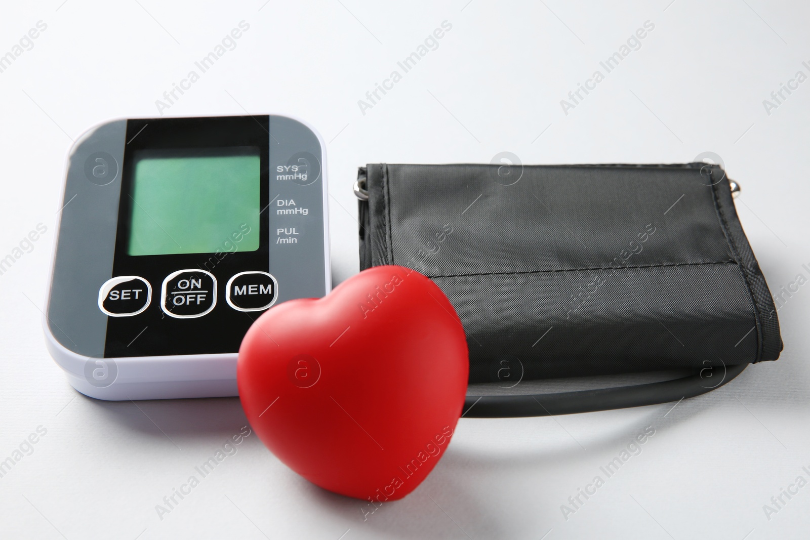 Photo of Blood pressure measuring device and squeeze heart on white background, closeup