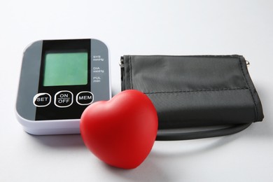 Photo of Blood pressure measuring device and squeeze heart on white background, closeup