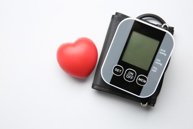 Blood pressure measuring device and squeeze heart on white background, top view