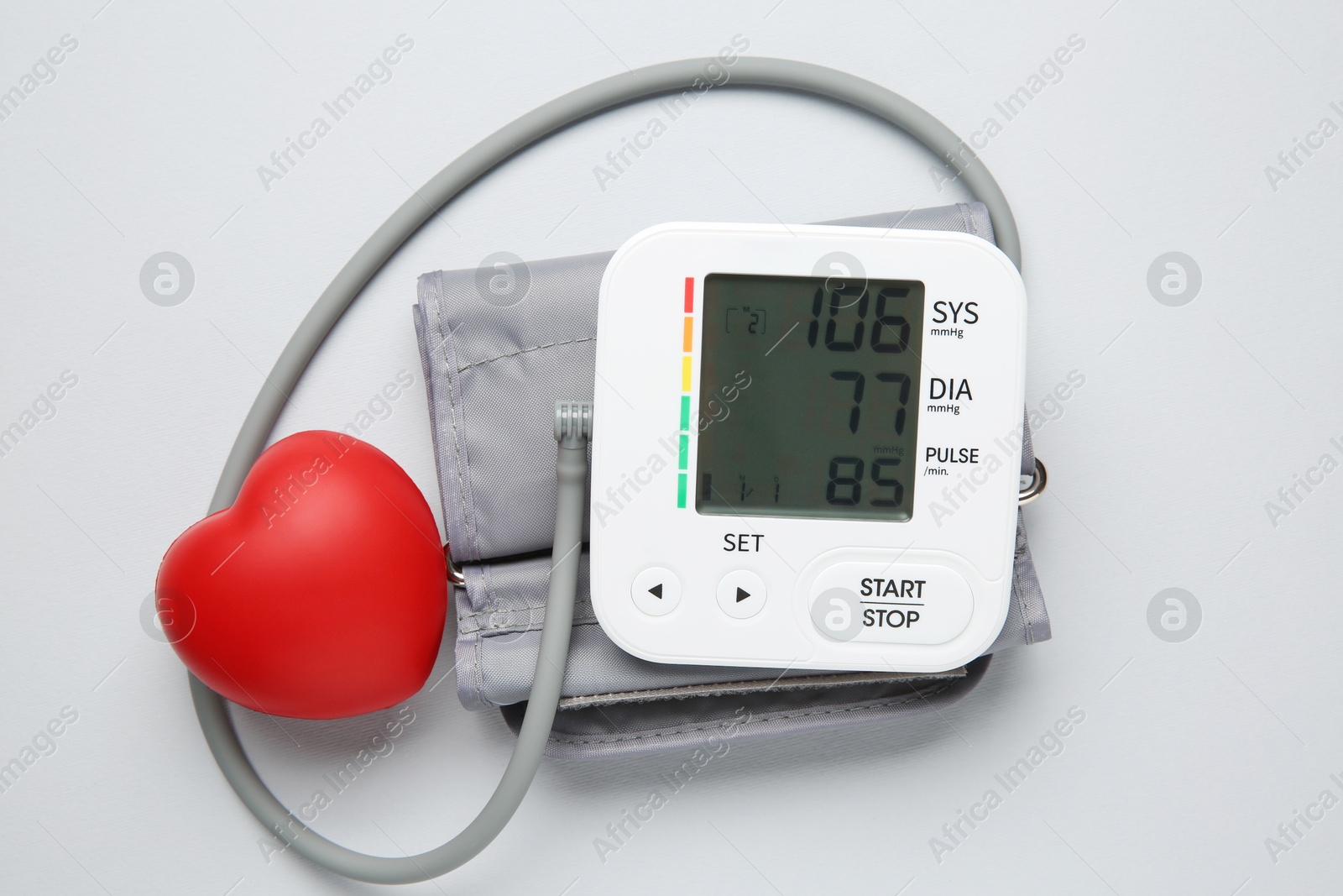 Photo of Blood pressure measuring device and squeeze heart on light grey background, top view