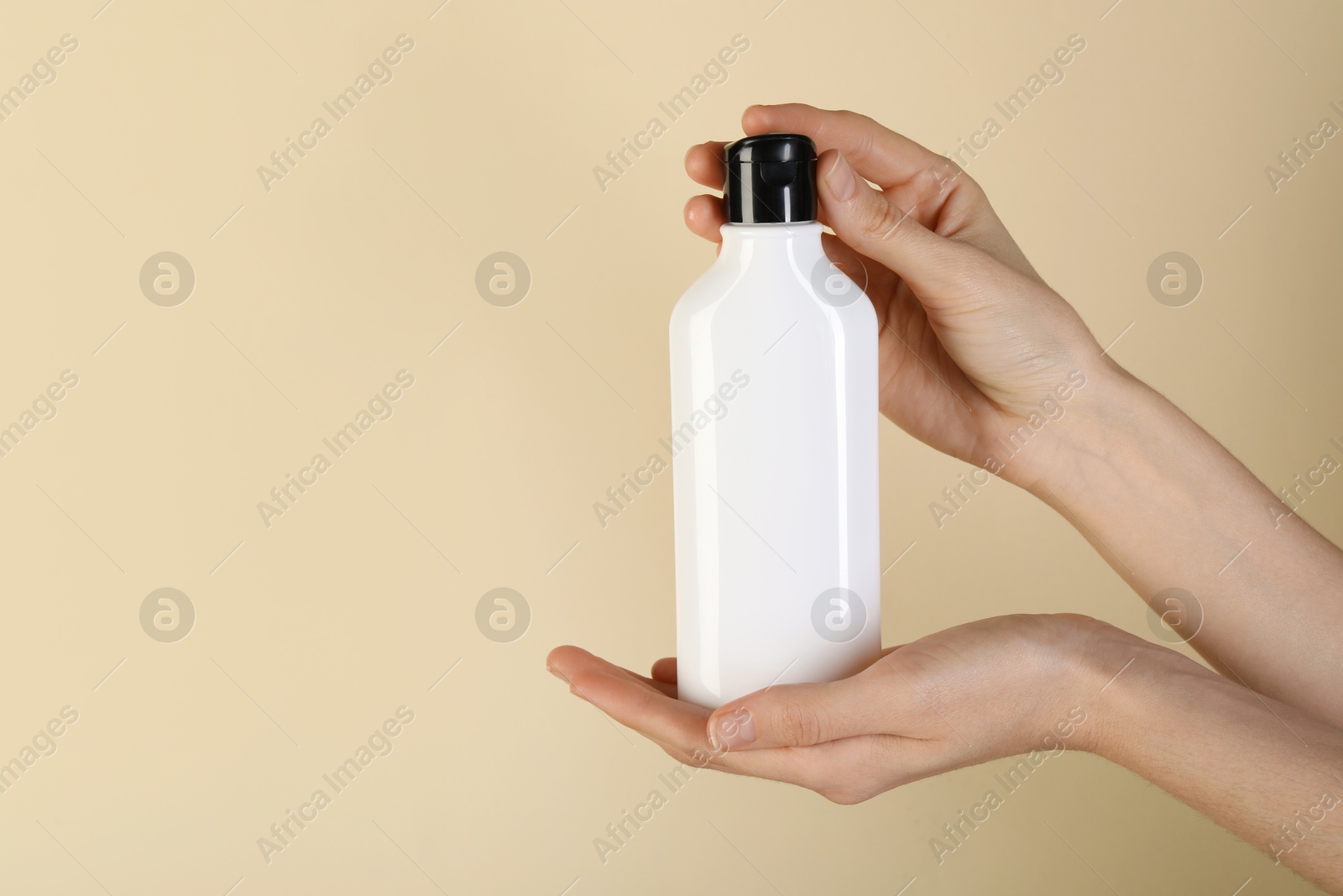 Photo of Woman with shampoo bottle on beige background, closeup. Space for text