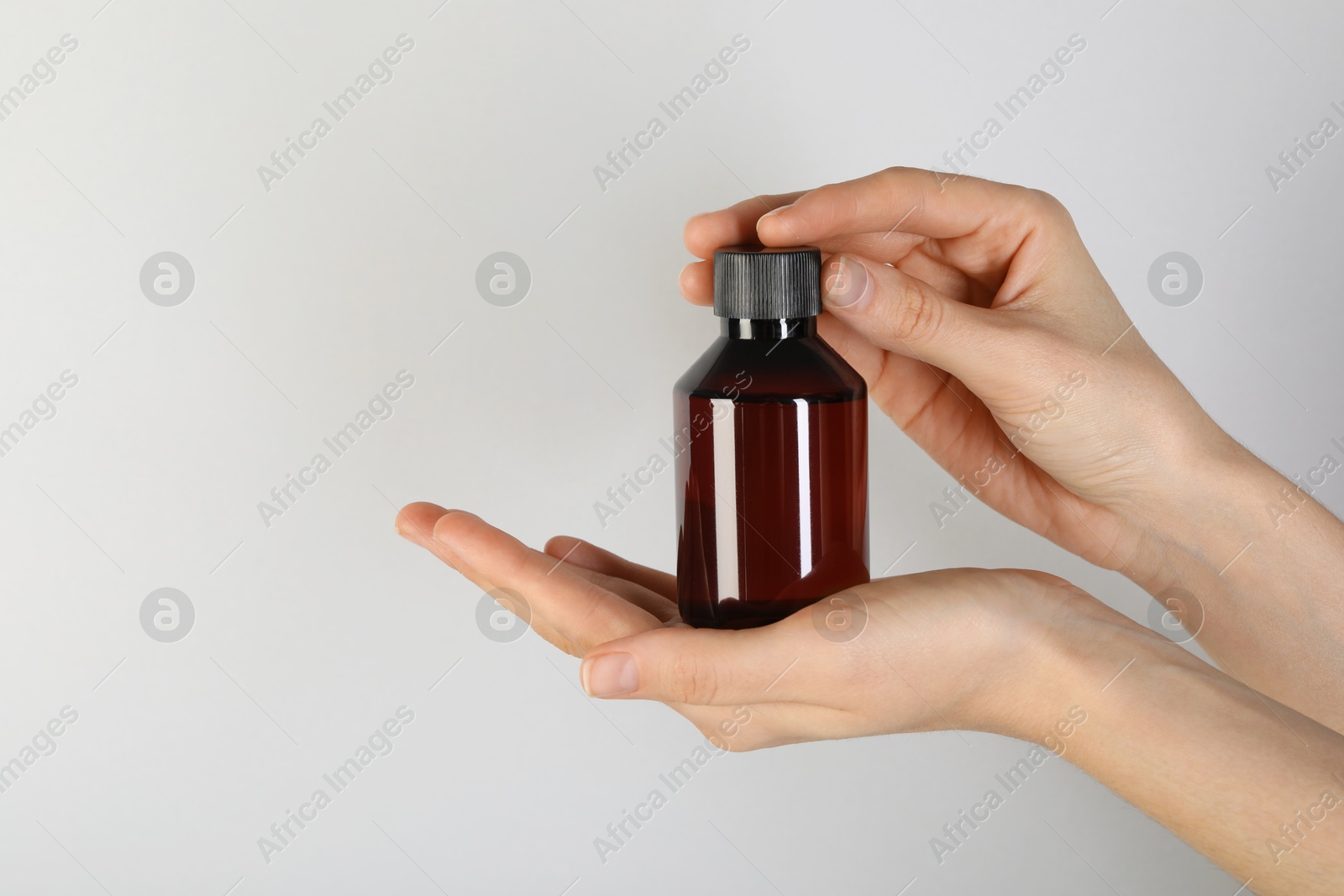 Photo of Woman with shampoo bottle on grey background, closeup