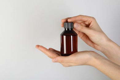 Photo of Woman with shampoo bottle on grey background, closeup