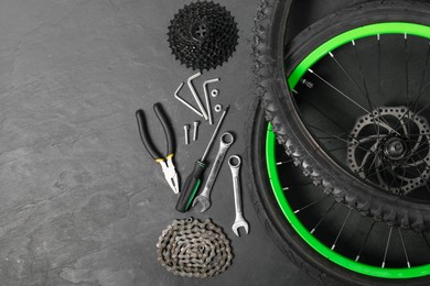 Photo of Parts of bicycle and tools on black background, flat lay