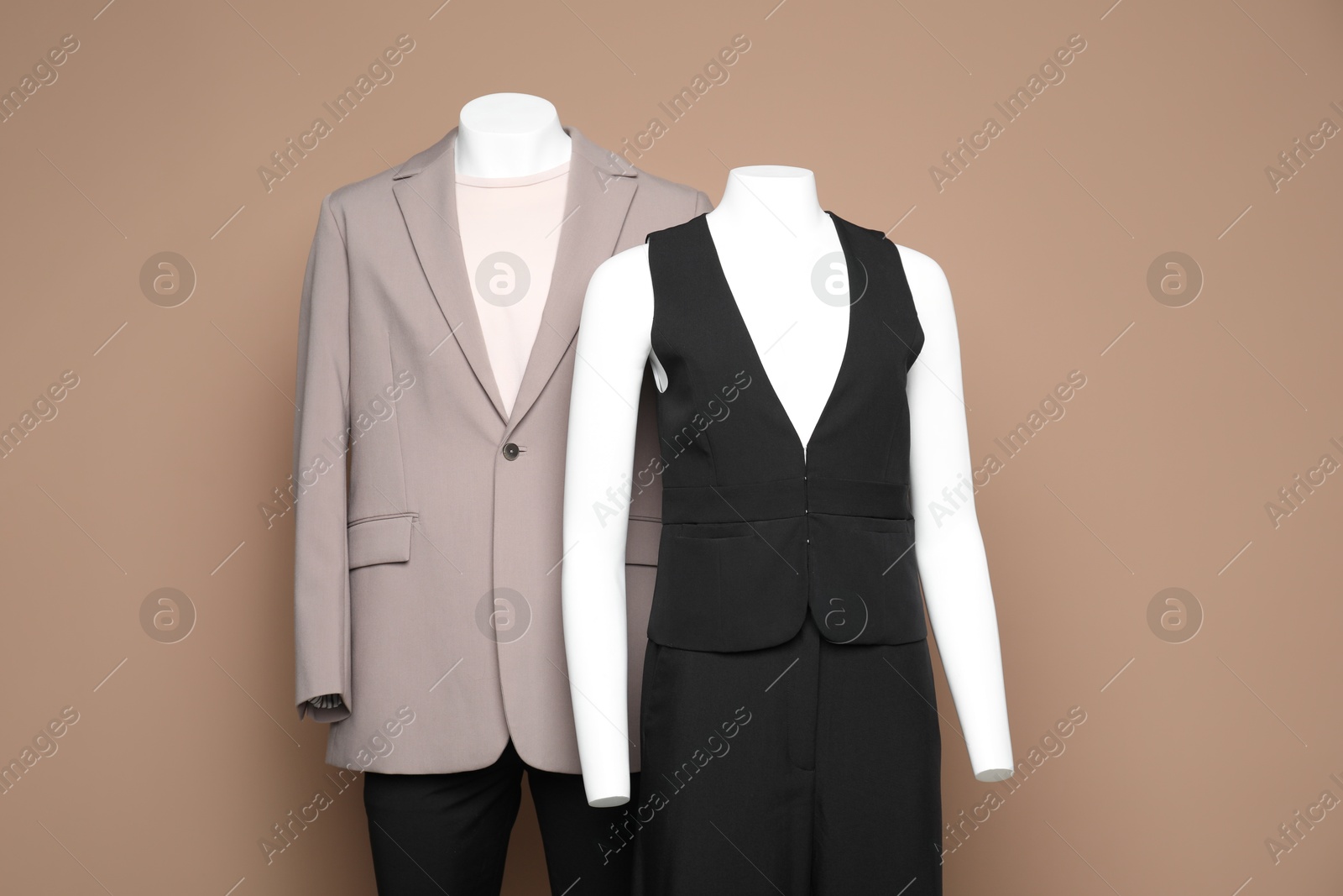 Photo of Female and male mannequins with stylish outfits on light brown background