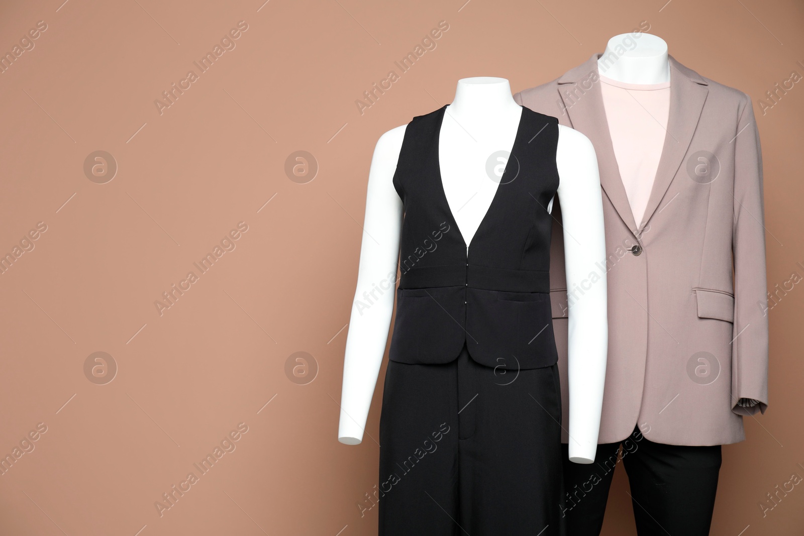 Photo of Female and male mannequins with stylish outfits on light brown background, space for text