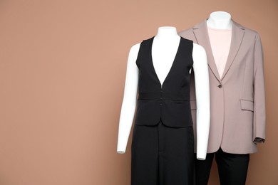 Photo of Female and male mannequins with stylish outfits on light brown background, space for text