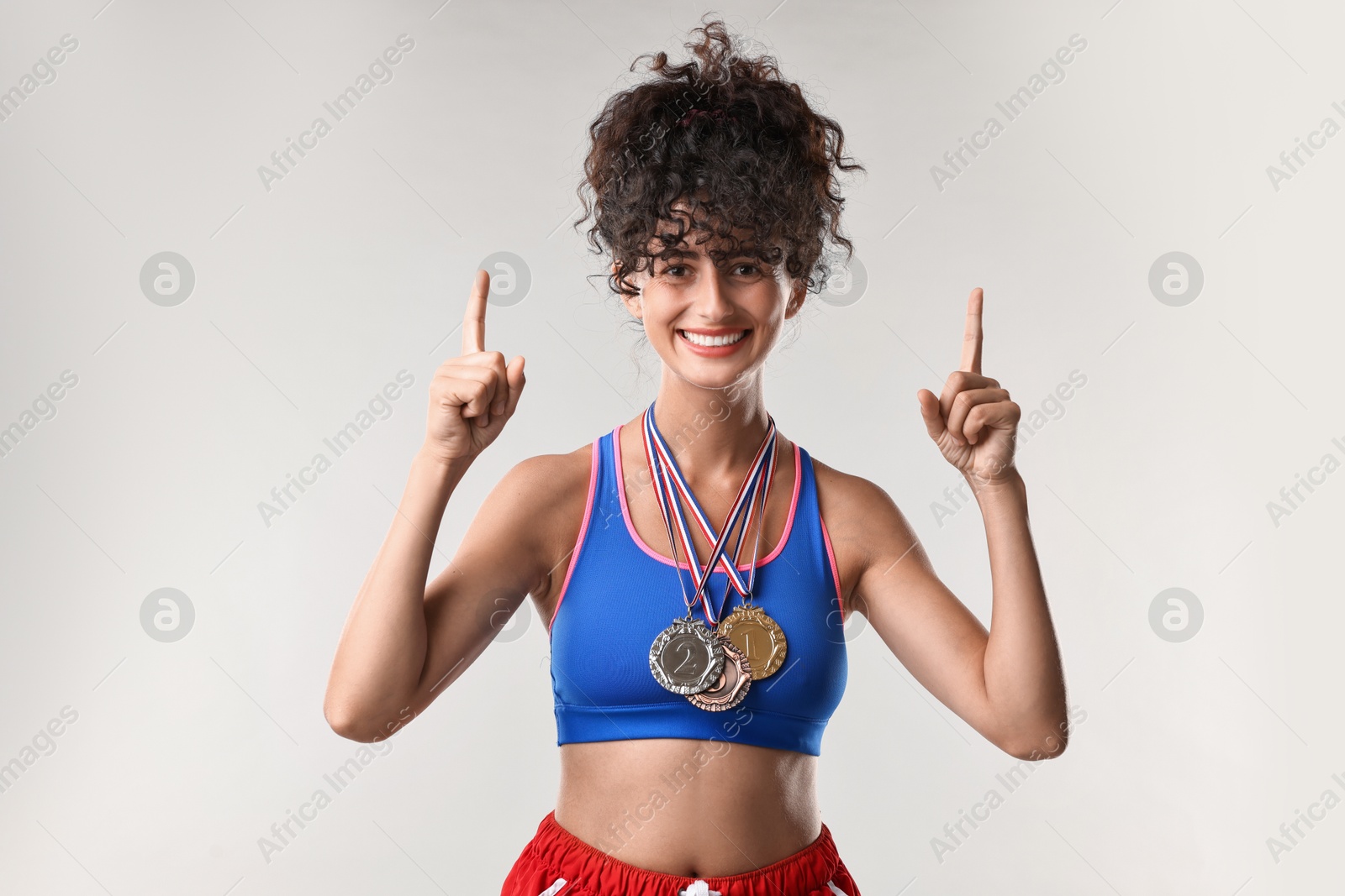 Photo of Happy winner with different medals upwards on light grey background