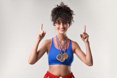 Photo of Happy winner with different medals upwards on light grey background