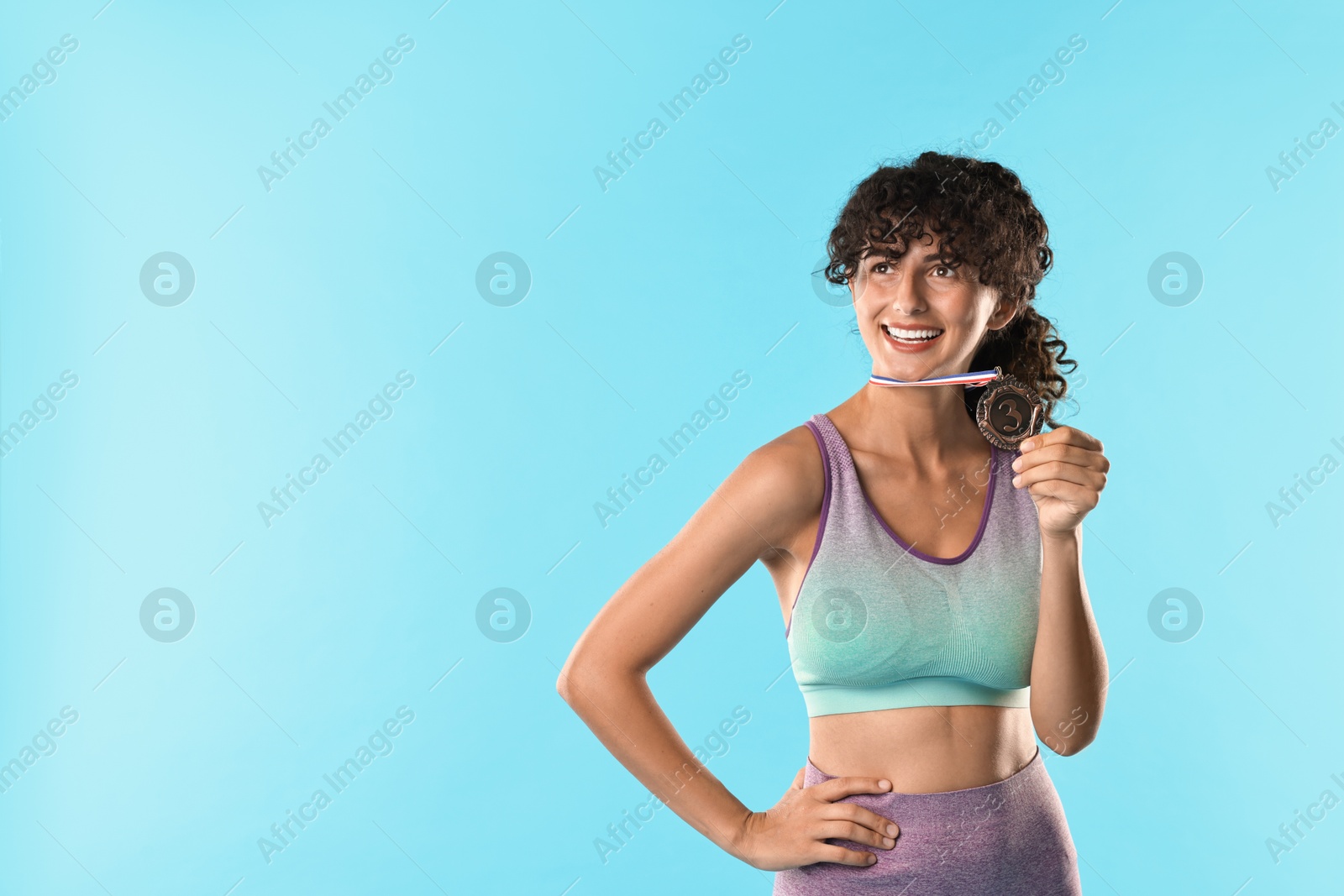 Photo of Happy winner with bronze medal on light blue background. Space for text