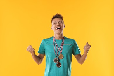 Happy winner with different medals on yellow background