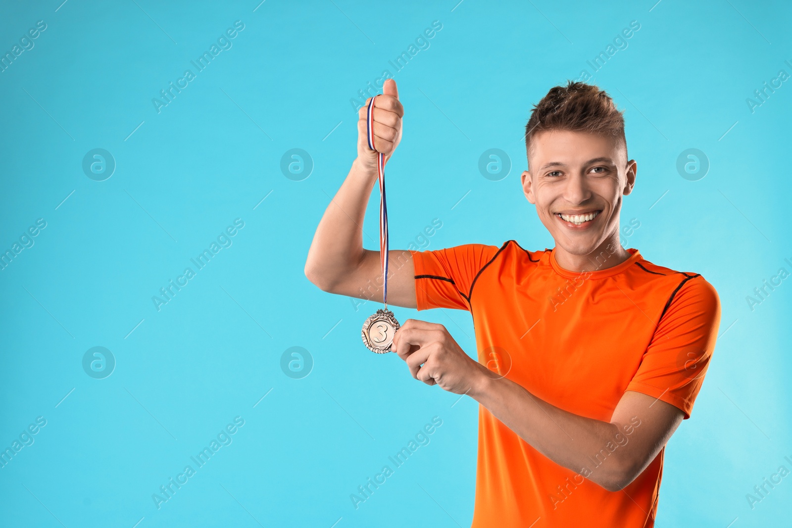 Photo of Happy winner with bronze medal on light blue background. Space for text