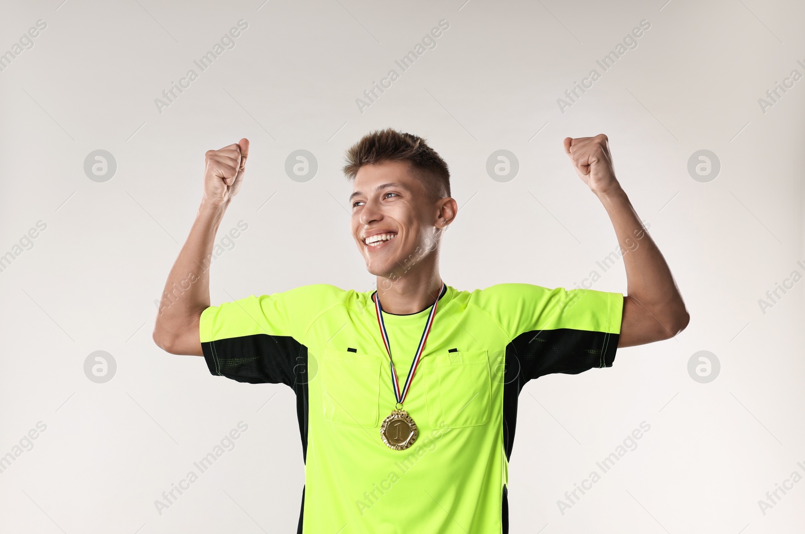 Photo of Happy winner with golden medal on light grey background