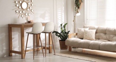 Photo of Bar stools near wooden table in room