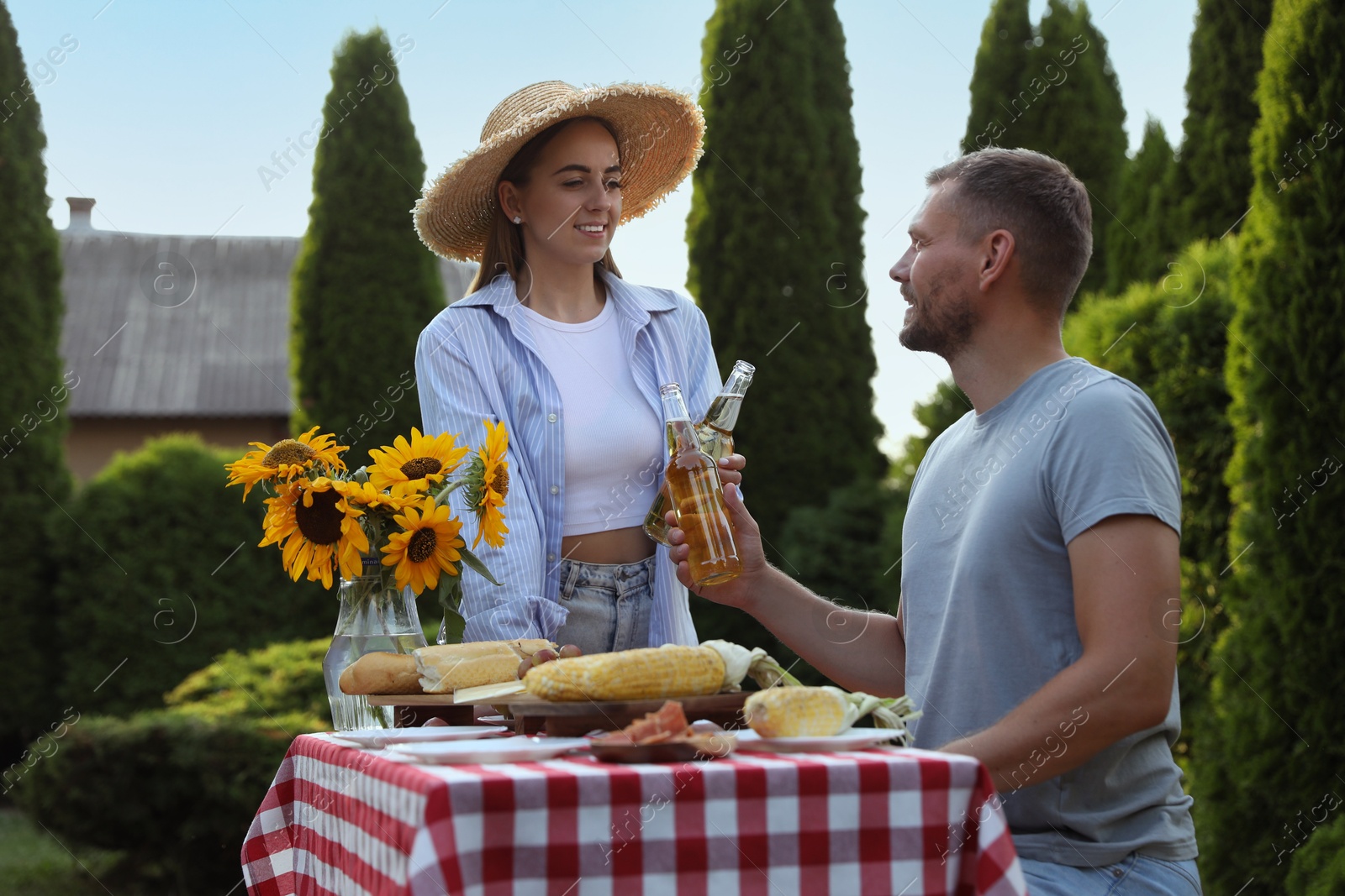 Photo of Friends with drinks enjoying picnic at table in garden