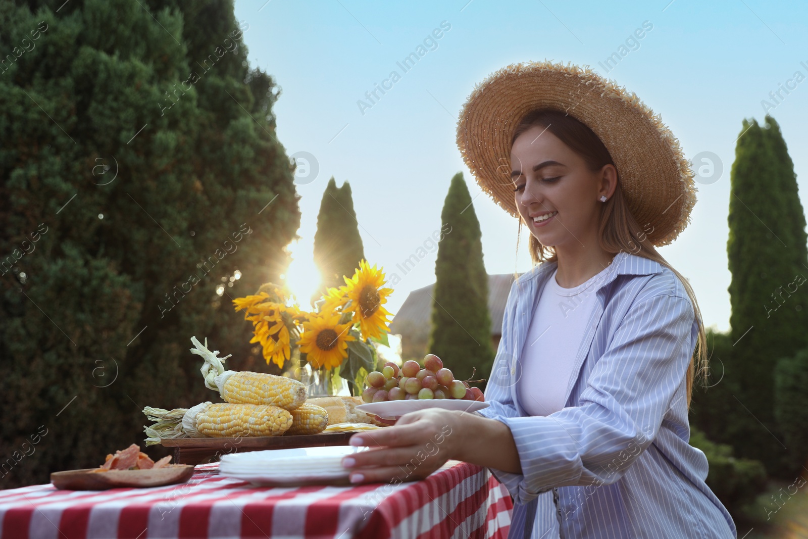 Photo of Woman setting table for picnic in garden