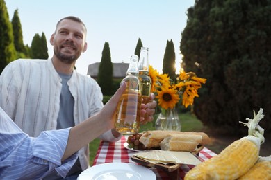 Photo of Friends with drinks enjoying picnic at table in garden, selective focus