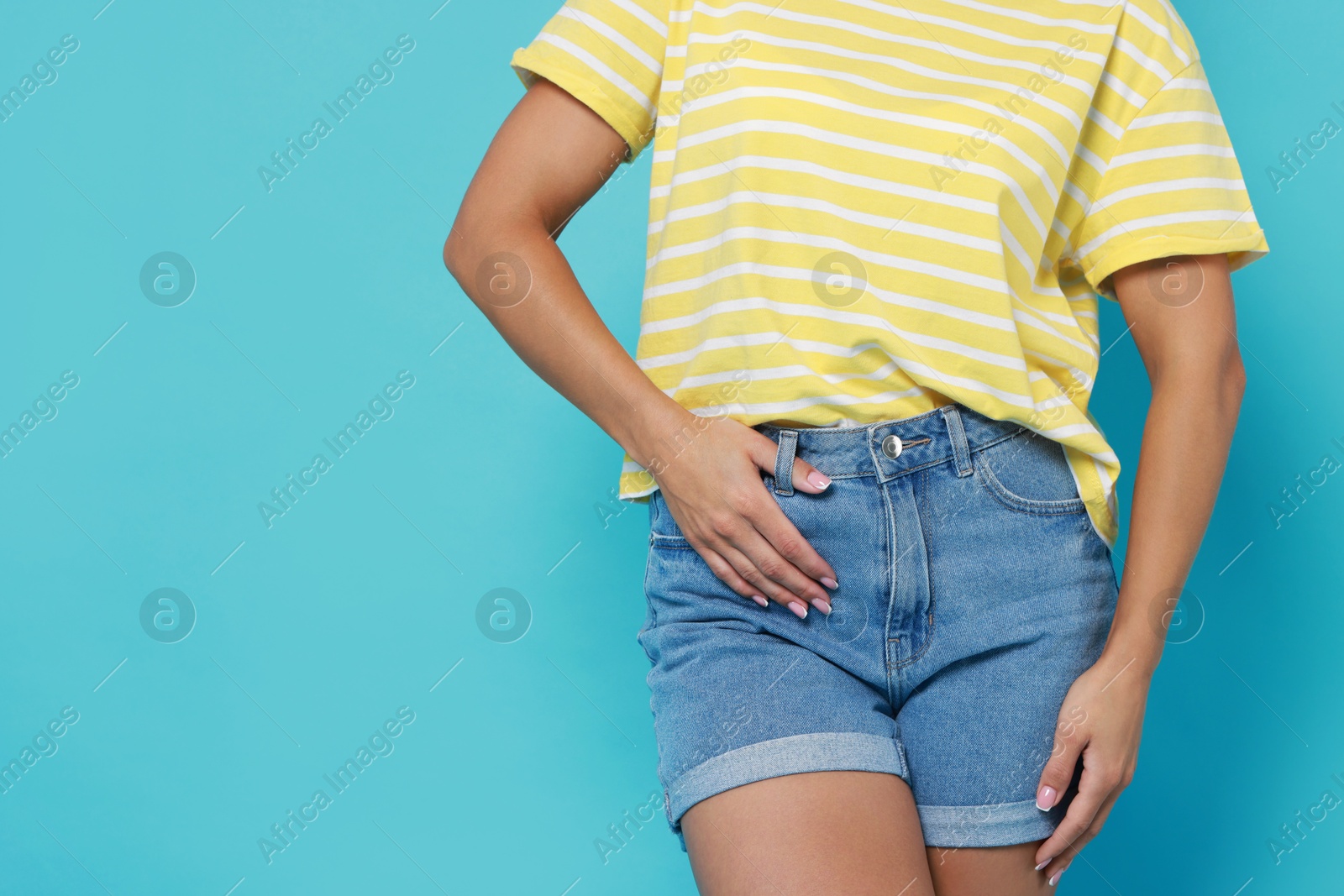 Photo of Woman wearing stylish denim shorts on light blue background, closeup. Space for text