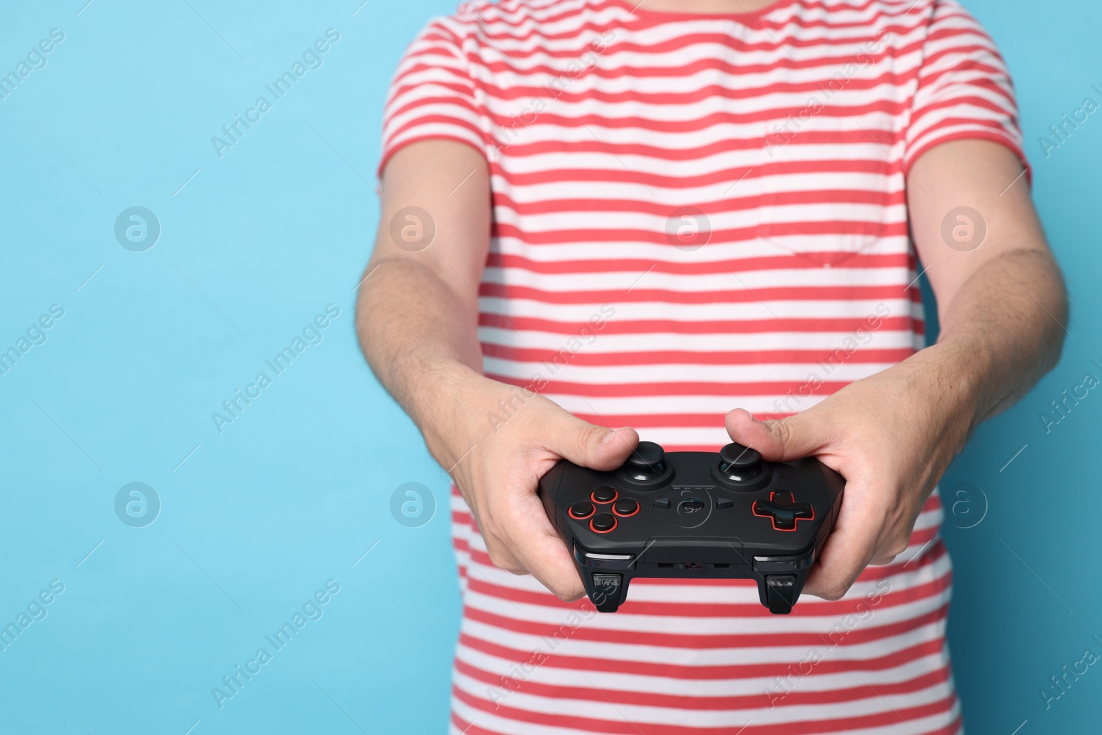 Photo of Man playing video games with controller on light blue background, closeup. Space for text