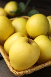 Photo of Fresh yellow apples in wicker basket on table, closeup