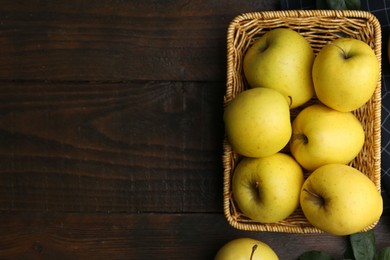 Photo of Fresh yellow apples in wicker basket on wooden table, top view. Space for text