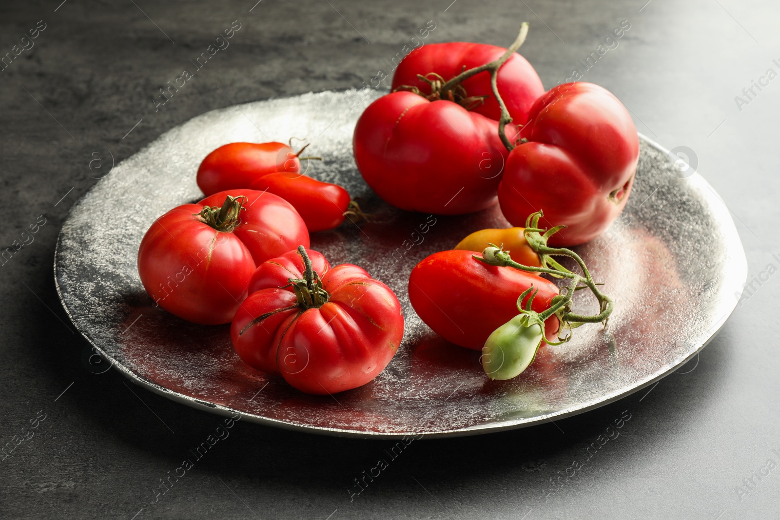 Photo of Different ripe and unripe tomatoes on grey table