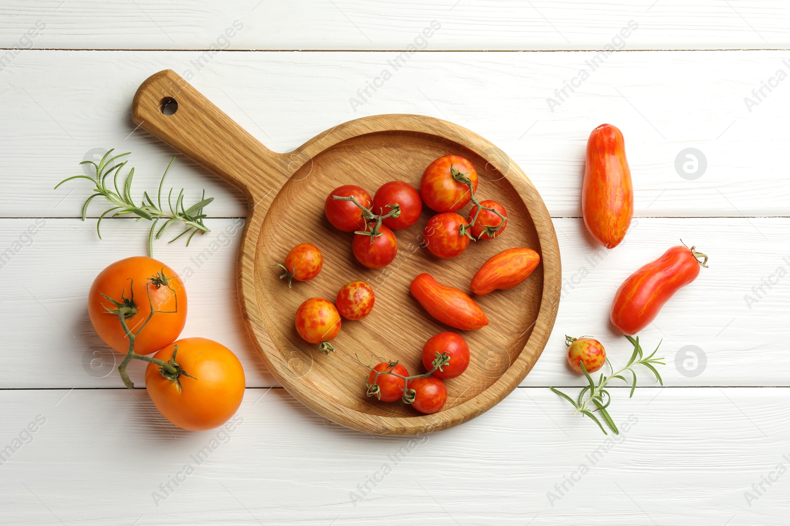 Photo of Different ripe tomatoes and rosemary on white wooden table, flat lay