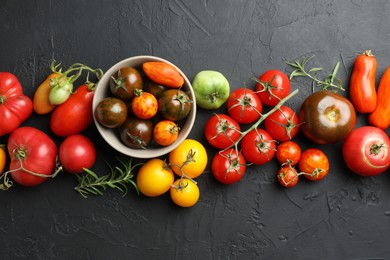 Photo of Different fresh tomatoes and rosemary on grey textured table, flat lay