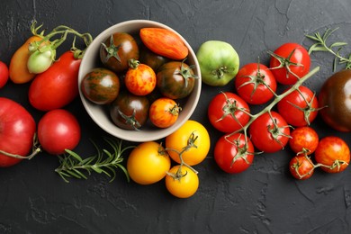 Photo of Different fresh tomatoes and rosemary on grey textured table, flat lay