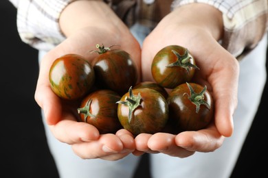 Photo of Woman holding fresh ripe tomatoes on black background, closeup