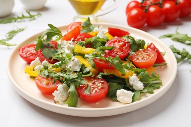 Photo of Tasty salad with arugula, cheese and vegetables on white tiled table, closeup