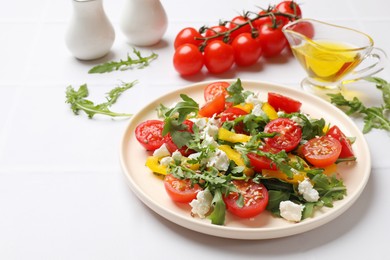 Photo of Tasty salad with arugula, cheese and vegetables on white tiled table