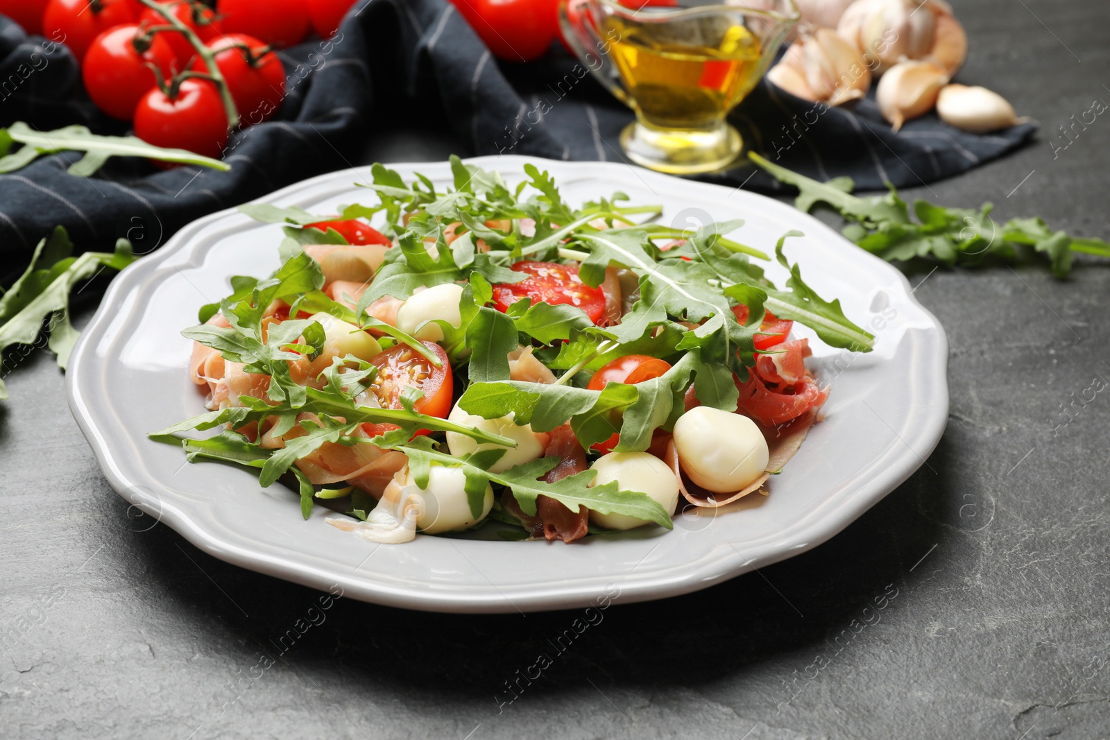 Photo of Tasty salad with arugula on dark textured table, closeup