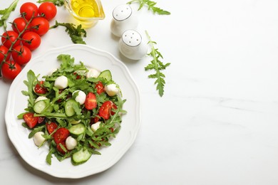 Photo of Tasty salad with arugula, mozzarella, tomatoes and cucumber on white marble table, flat lay. Space for text