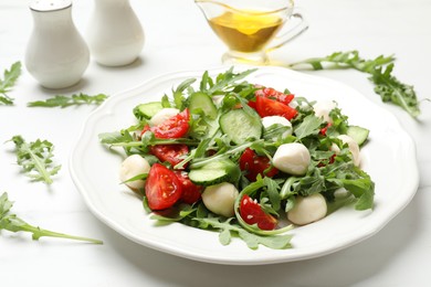 Photo of Tasty salad with arugula, mozzarella, tomatoes and cucumber on white table, closeup