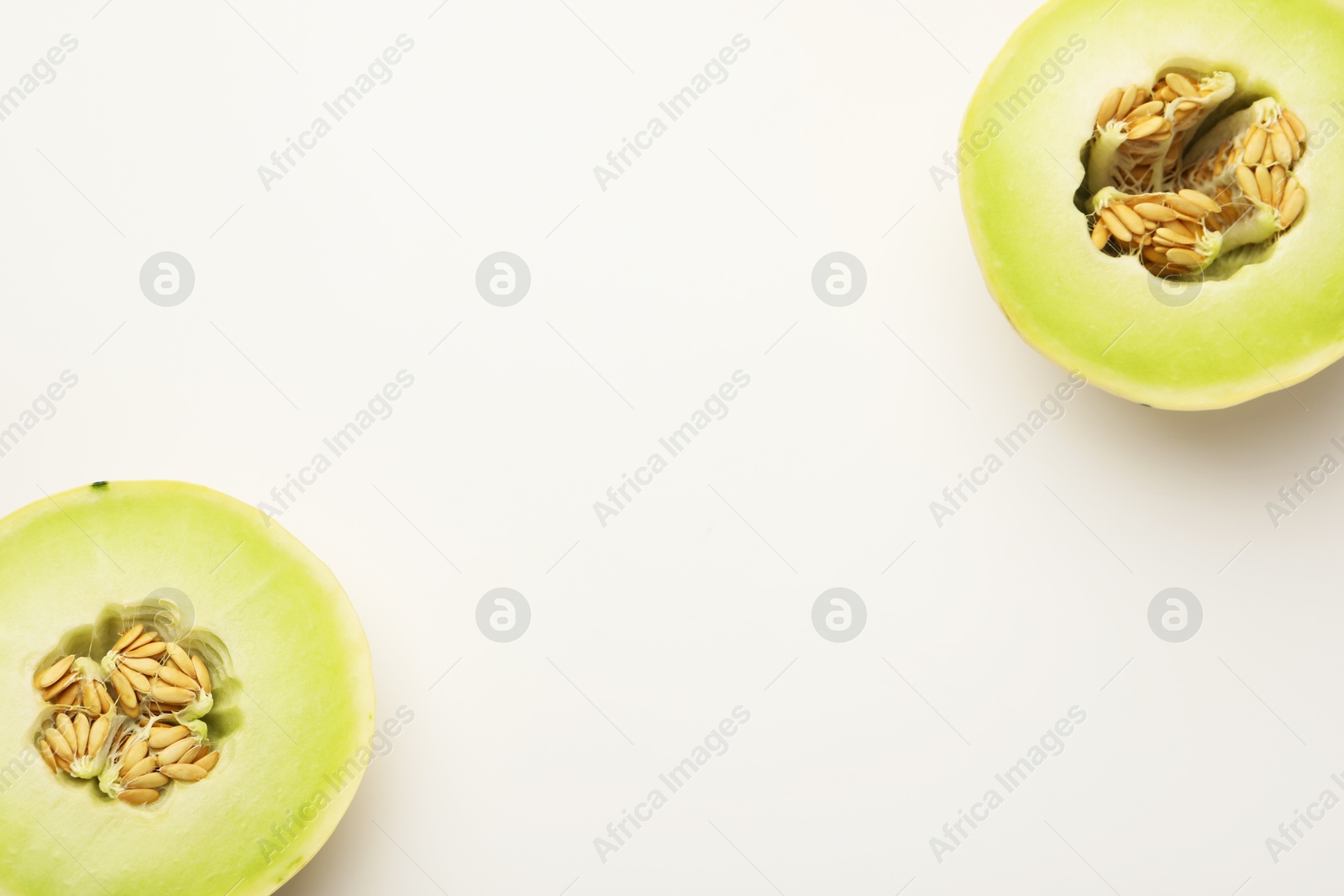 Photo of Halves of fresh ripe honeydew melon on white background, top view. Space for text