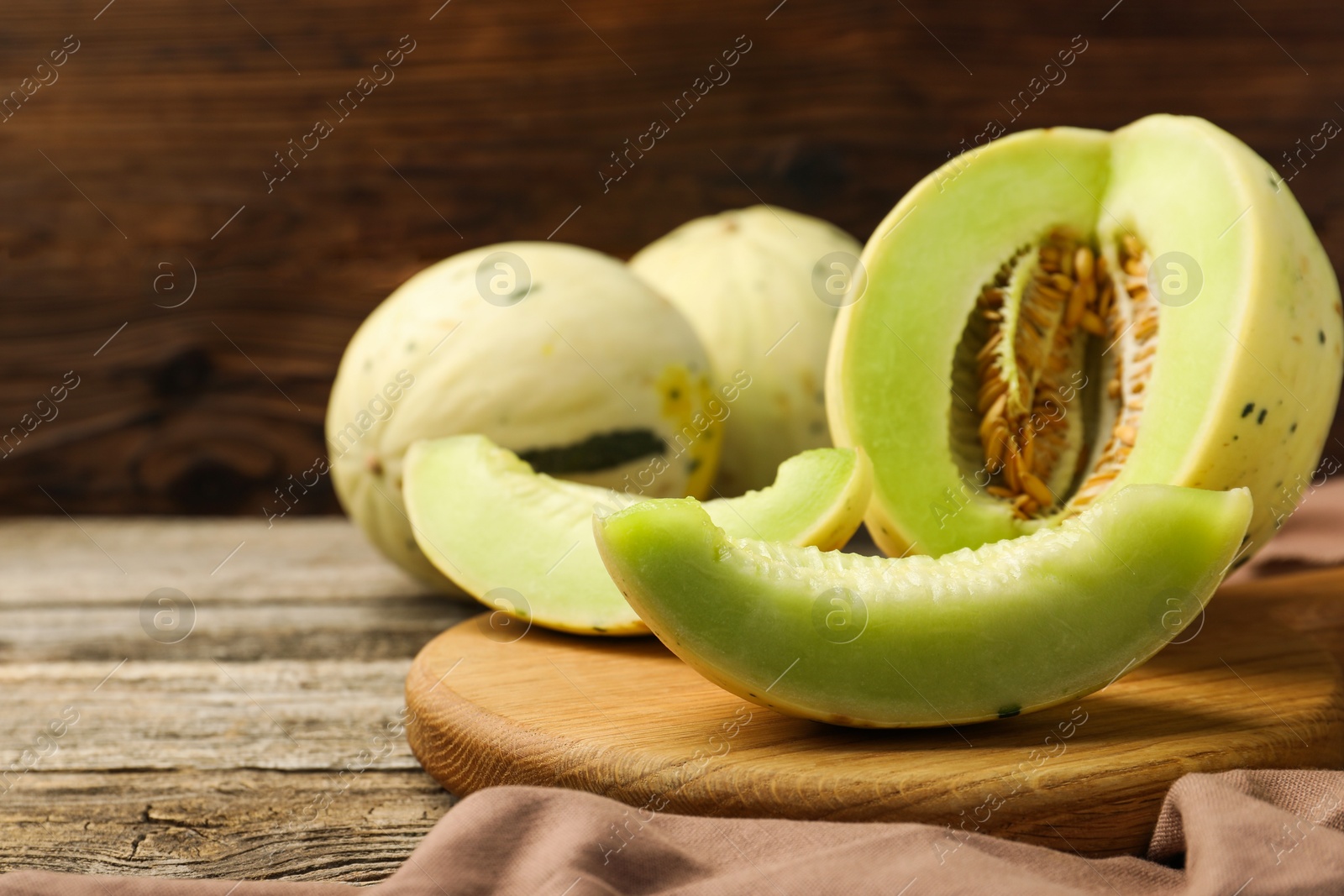 Photo of Fresh whole and cut honeydew melons on wooden table. Space for text